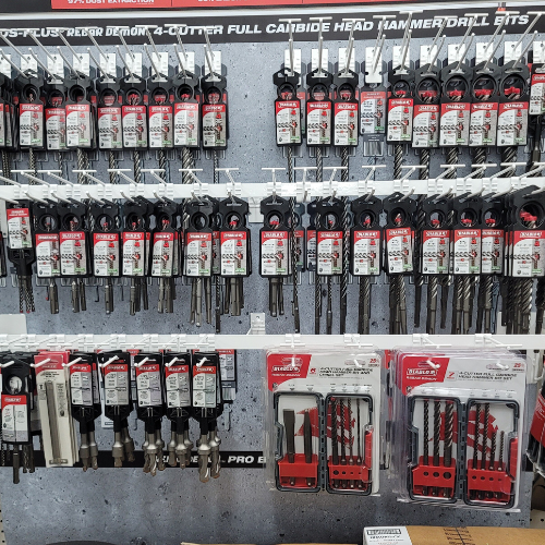 Display of Milwaukee brand drill bits and accessories, featuring a variety of sizes and types, arranged on a wall in a hardware store.