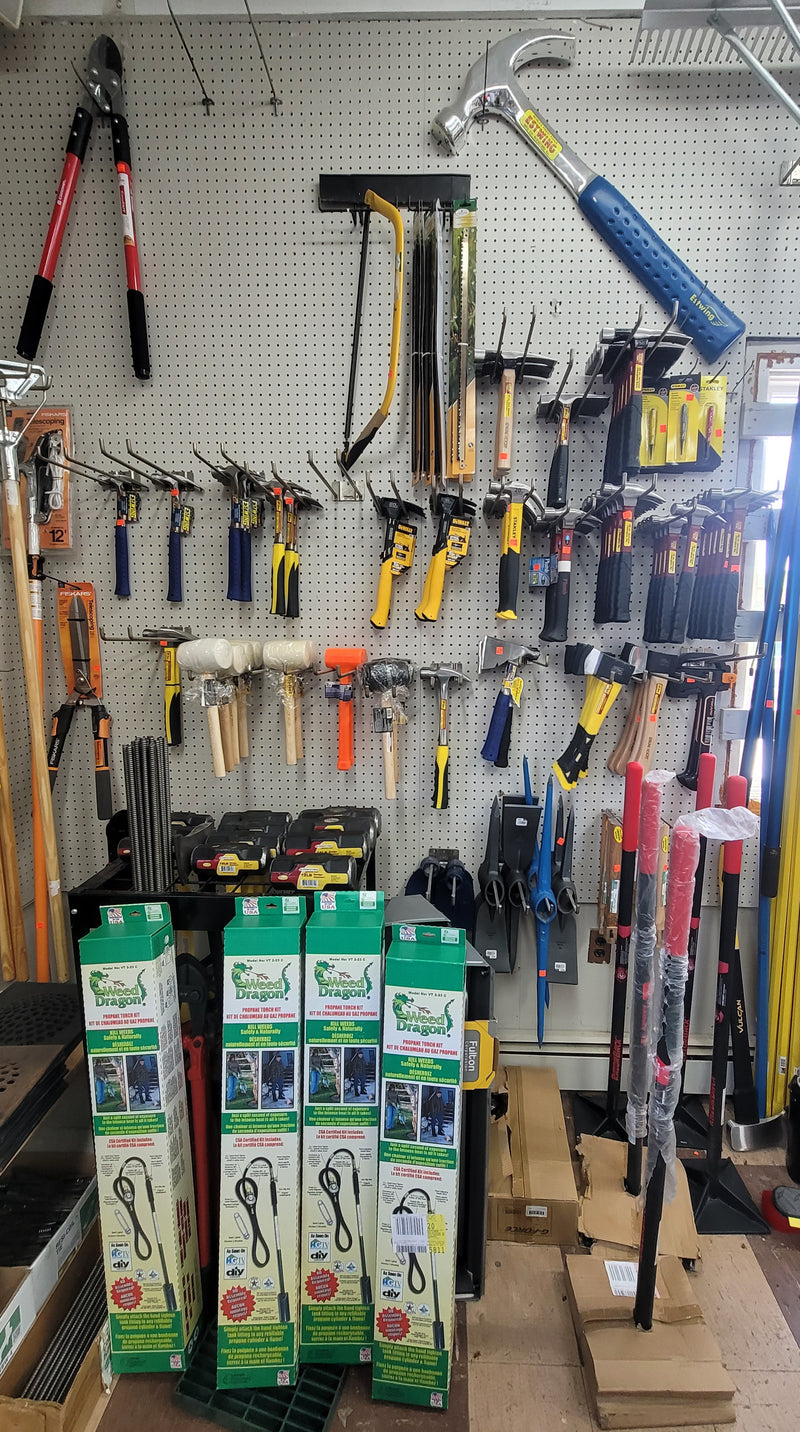 Wall filled with hammers and mallets of various sizes and from various brands with a Weed Dragon Propane Torch Kit in front