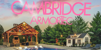 A pool area featuring Cambridge with Armortec Pavingstones, complemented by a pavilion with seating and a built-in fireplace. Across the pool, chairs and a pool house are nestled amidst lush greenery under a pink, blue, and purple sky.